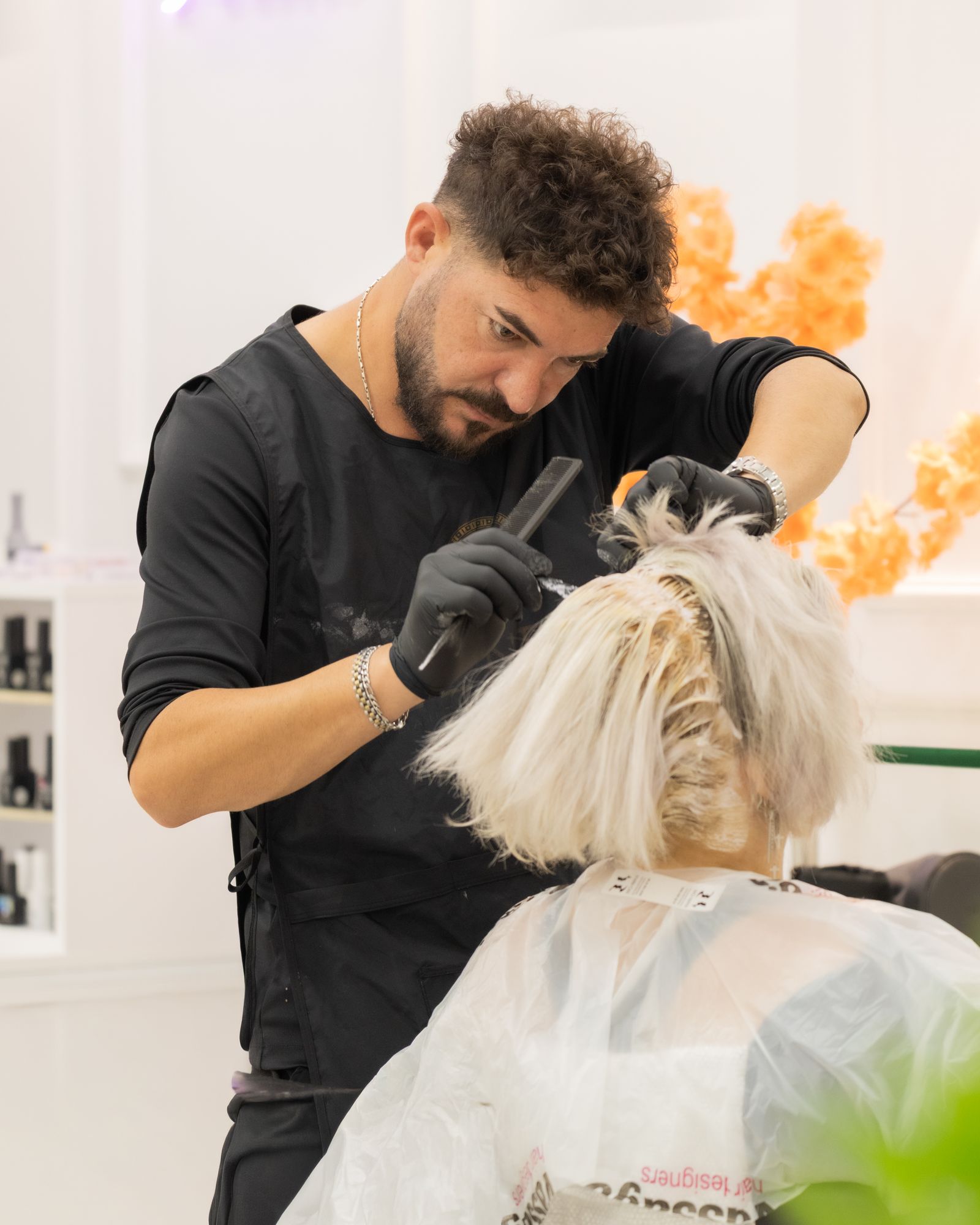 A stylist carefully colouring a client's hair in a bright salon