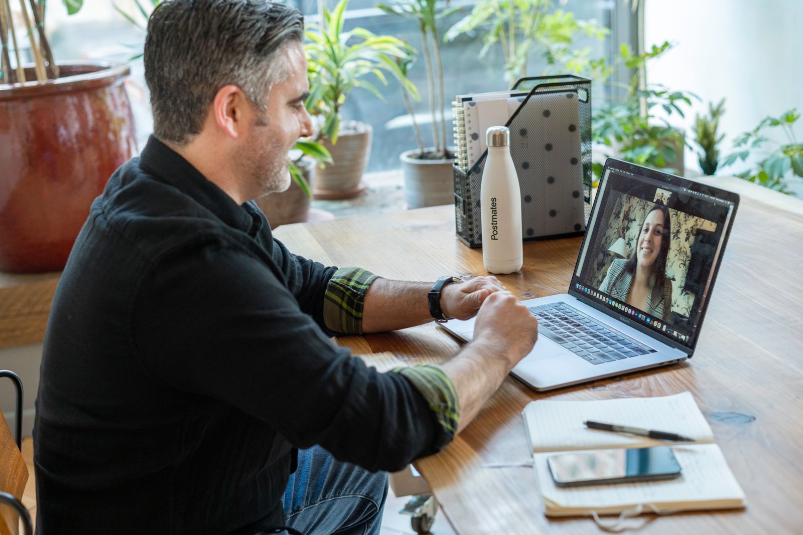 A man meeting with a woman over a video call from a bright workspace